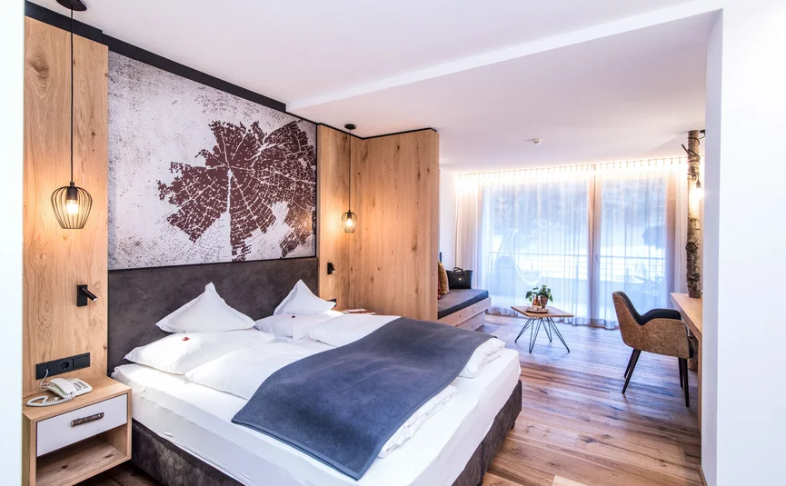 Modernes Hotelzimmer mit Doppelbett, Holzakzenten und großen Fenstern