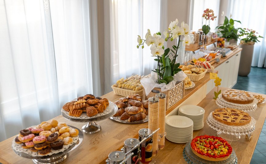 Buffet with pastries, cakes, fruit tart, and flowers on a wooden table