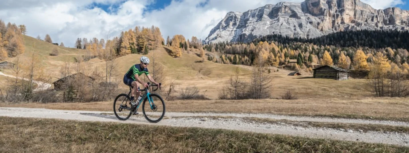 Cyclist riding a gravel bike on a path in an autumn mountain landscape