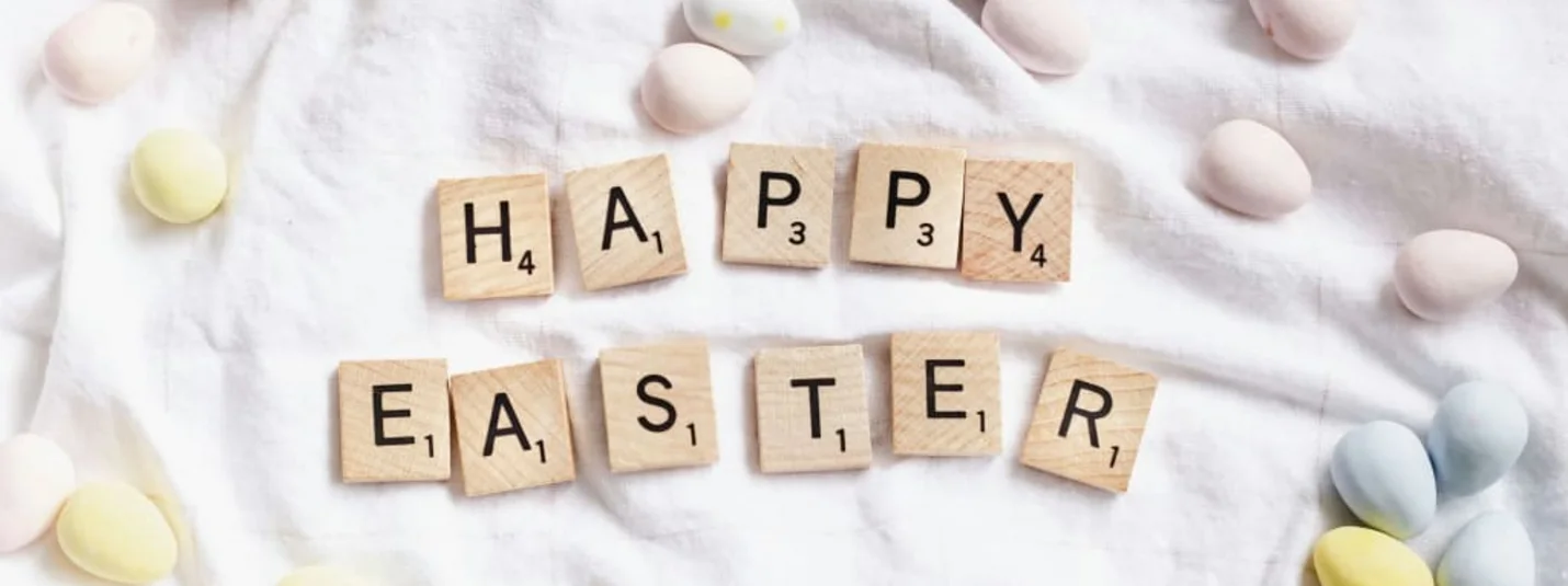 Scrabble letters vormen Happy Easter op wit doek met pastel gekleurde eieren