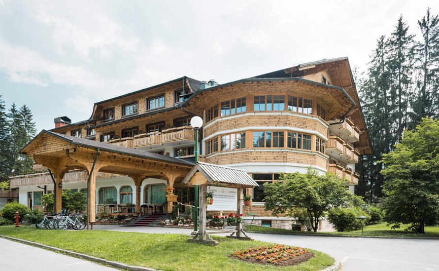 Grande edificio dell'hotel in legno con ingresso coperto e biciclette in ambiente verde