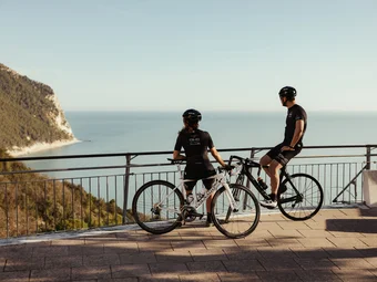 Marche © Alex Moling Two cyclists admire the sea view from a scenic overlook.