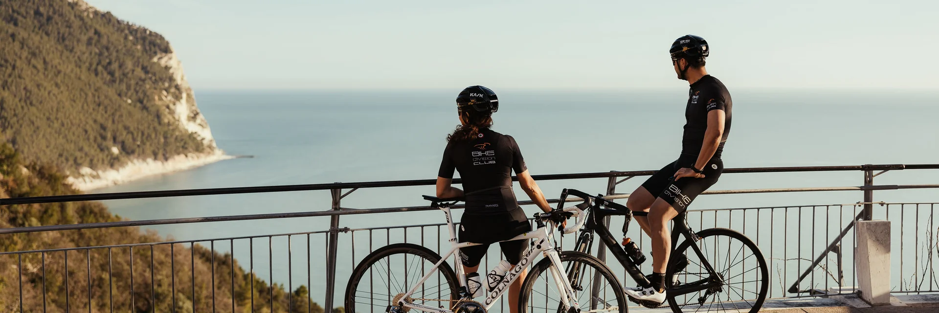 Zwei Radfahrer genießen den Blick auf das Meer von einer Aussichtsplattform.