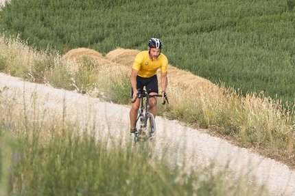 Fietser op kronkelig pad door groene en gele velden