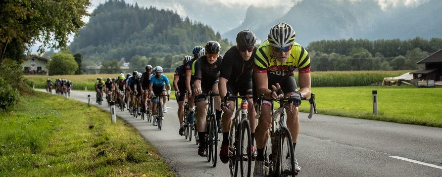 Maratona ciclistica del Kufsteinerland © Erwin Haiden Ciclisti in gruppo su strada di campagna con montagna e nuvole sullo sfondo