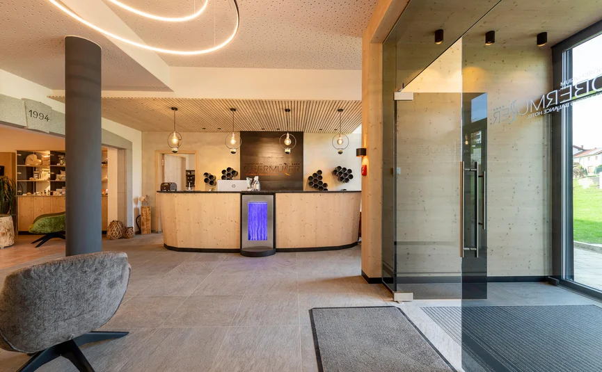 Moderner Hotel-Empfangsbereich mit Holztheke und Glas-Eingangstür