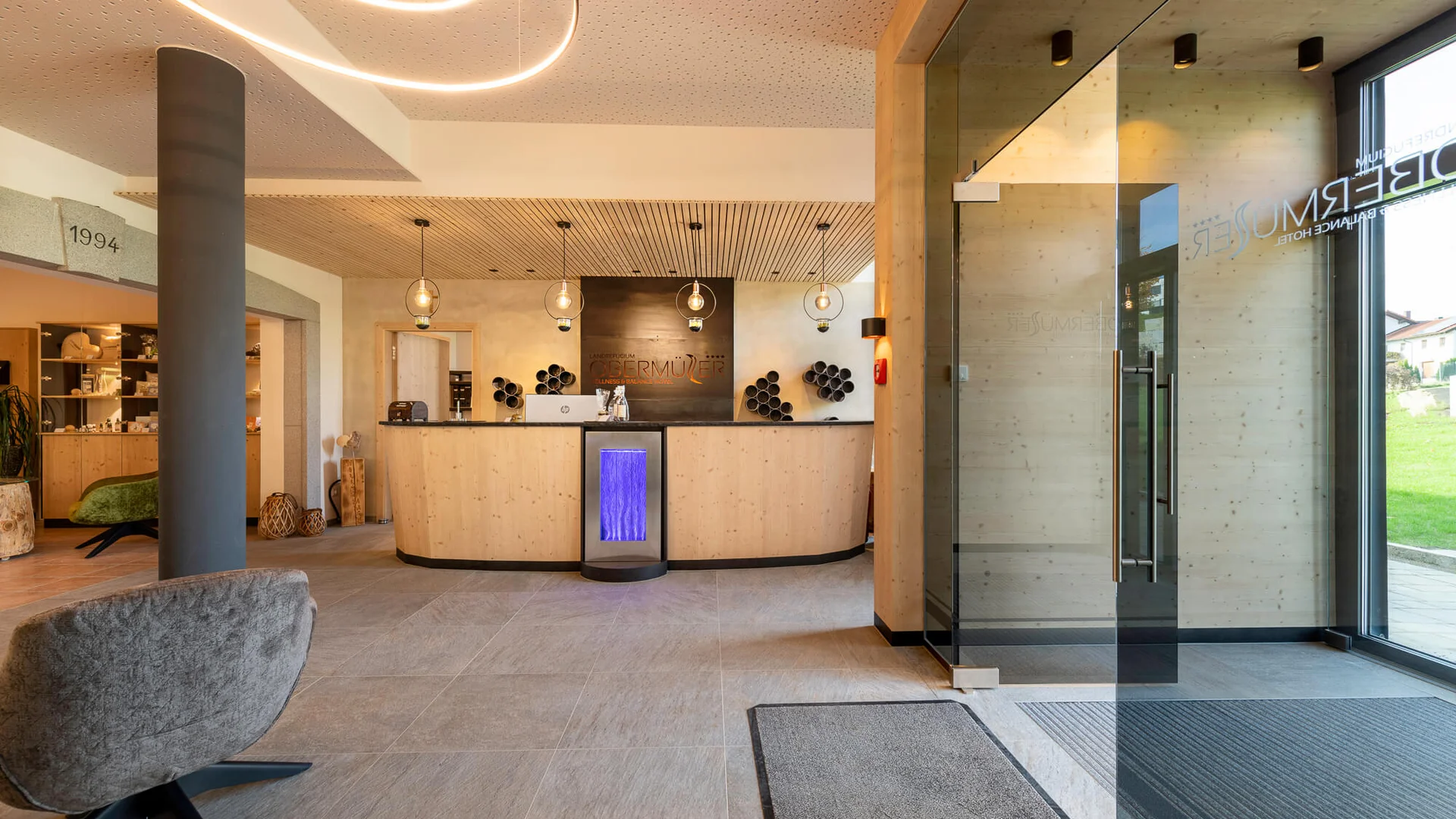 Moderner Hotel-Empfangsbereich mit Holztheke und Glas-Eingangstür