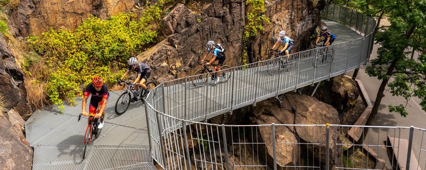 Radfahrer fahren auf einer Metallbrücke durch felsiges Gelände