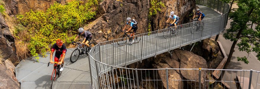 Radfahrer fahren auf einer Metallbrücke durch felsiges Gelände