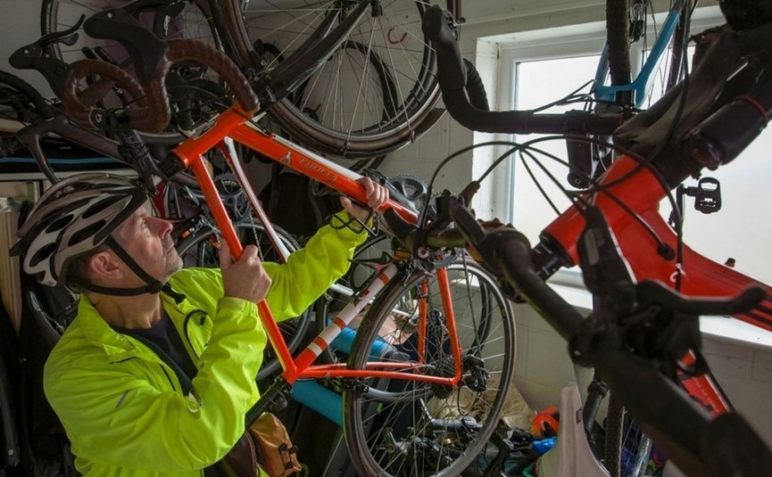 Hotel Boka *** © Hotel Boka Mann in Fahrradhelm hebt orangefarbenes Fahrrad in Fahrradkeller