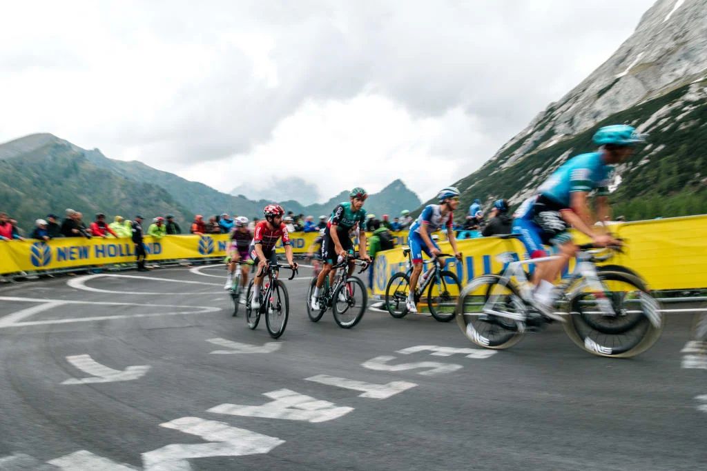 Ciclisti in gara su una strada di montagna tortuosa con spettatori