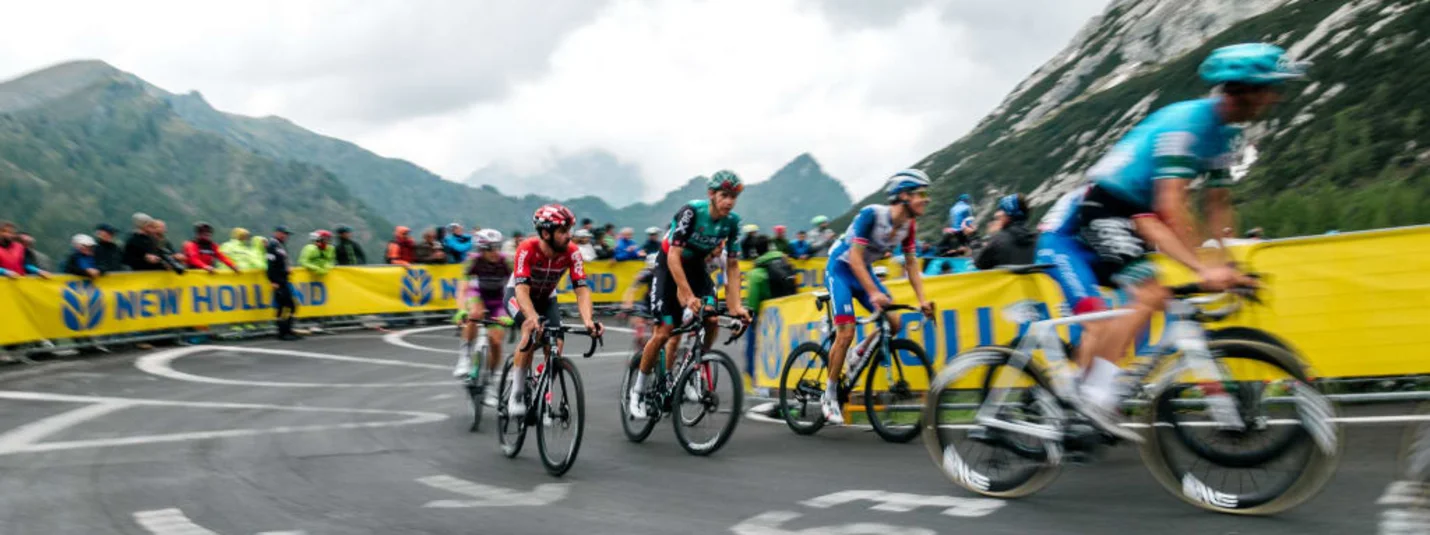 Giro d'Italia Weekend Radrennfahrer fahren eine kurvige Bergstraße mit Zuschauern im Hintergrund