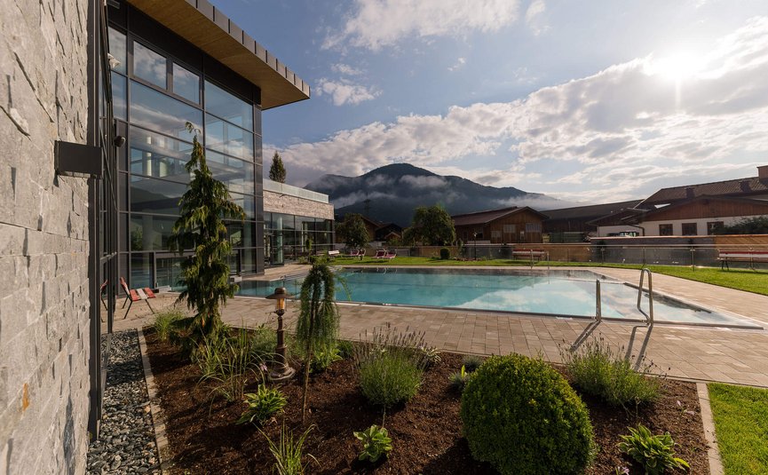 Modern pool next to glass building with mountain view at sunset