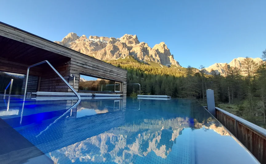 Hotel Gran Paradiso **** © Davide dal Mas Infinity-Pool mit Bergblick und Holzhaus bei klarem Himmel