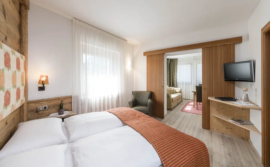 Helles Hotelzimmer mit Doppelbett und angrenzendem Wohnzimmer