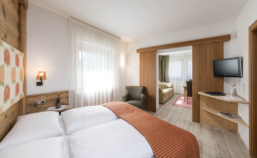 Bright hotel room with double bed and connected living area