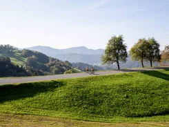 Valle della Savinja © Kaja Ribezl Due ciclisti su una strada in un paesaggio collinare con alberi e montagne