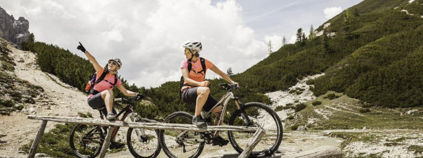 Due ciclisti su un ponte di legno in paesaggio montano