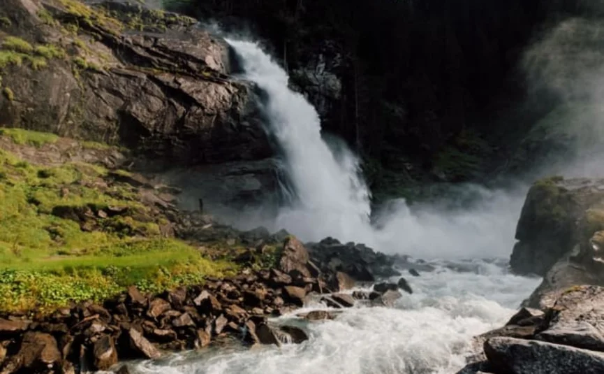 Cascata in paesaggio montano boscoso con acqua corrente e rocce