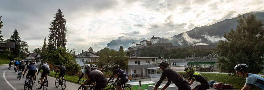 Gruppe Radfahrer auf Landstraße mit Schloss und Bergen im Hintergrund