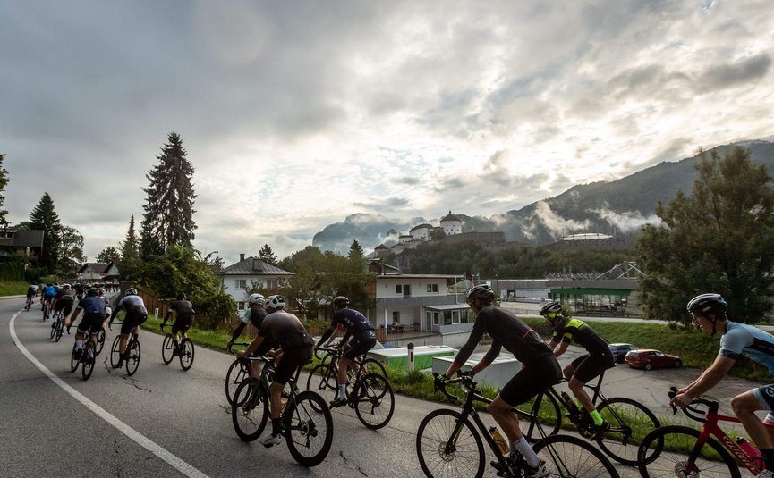 Groep fietsers op landweg met kasteel en bergen op de achtergrond