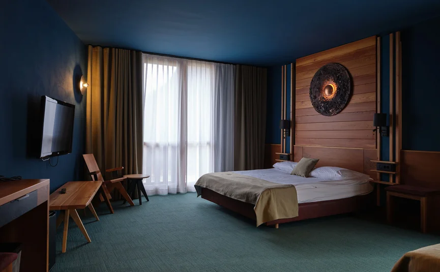 Camera d'hotel moderna con letto grande e dettagli in legno