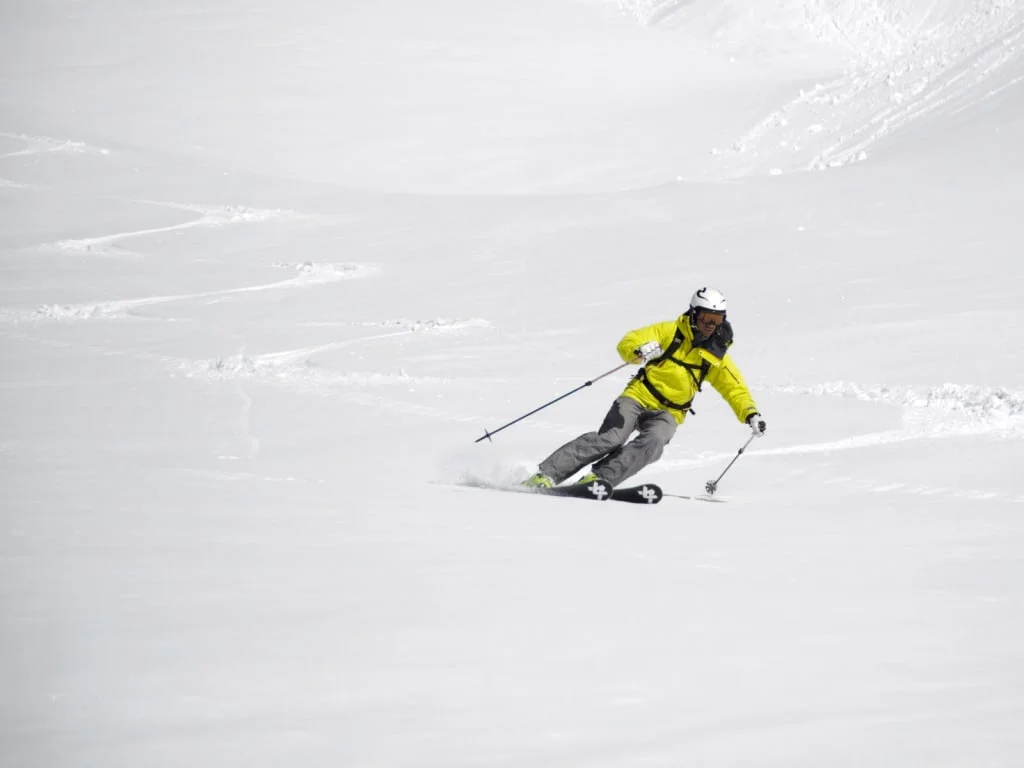 Skieër in gele jas skiet op verse sneeuw