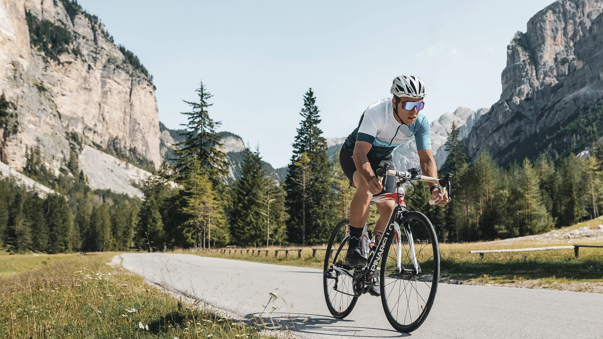 Fahrradfahrer fährt auf Bergstraße mit Felsen und Bäumen im Hintergrund