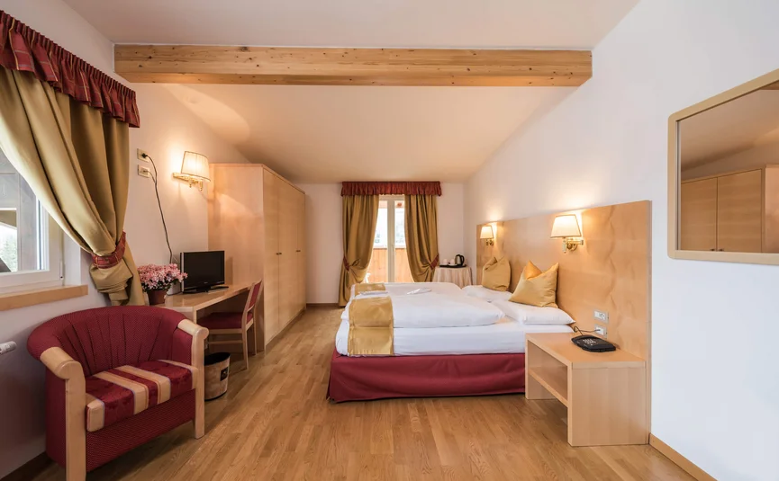 Helles Hotelzimmer mit Doppelbett, Stuhl, Schreibtisch und Balkon