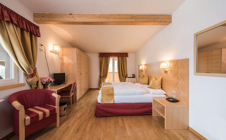 Helles Hotelzimmer mit Doppelbett, Stuhl, Schreibtisch und Balkon