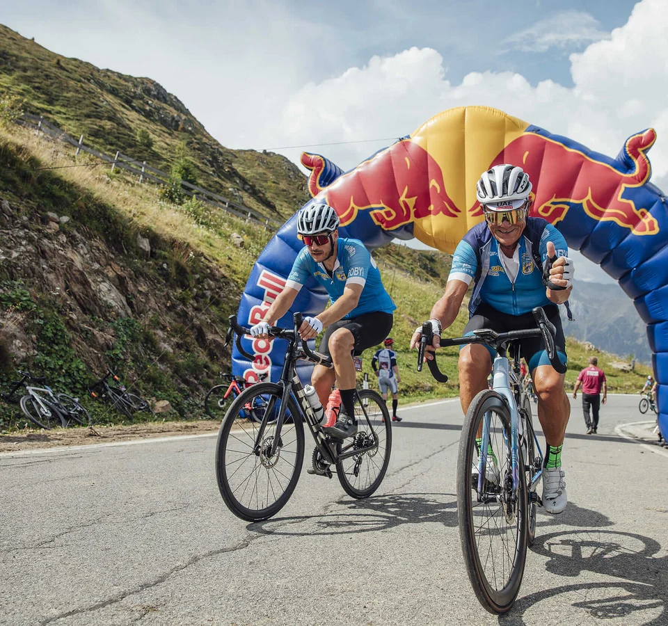 Ciclisti che passano sotto un arco gonfiabile Red Bull durante una gara in montagna