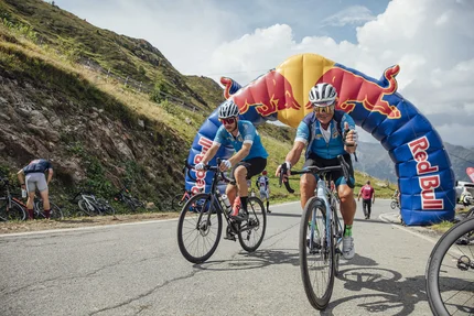 Fietsers onder een opgeblazen Red Bull-boog tijdens een bergrace