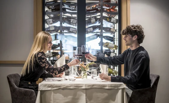 Coppia che brinda con bicchieri di vino rosso al ristorante