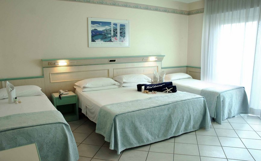 Camera d'hotel con tre letti singoli e copriletti blu