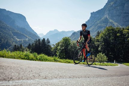 Cyclist wearing helmet rides on mountain road on a sunny day