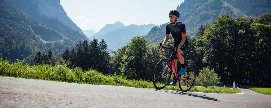 Wielrenner met helm rijdt op bergweg bij zonnig weer