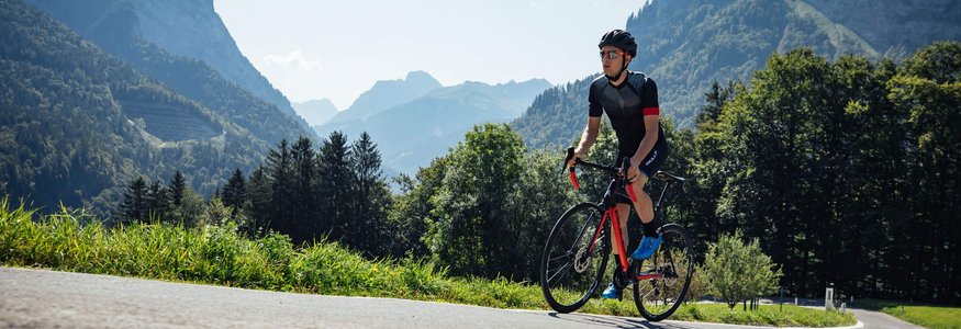 Cyclist wearing helmet rides on mountain road on a sunny day