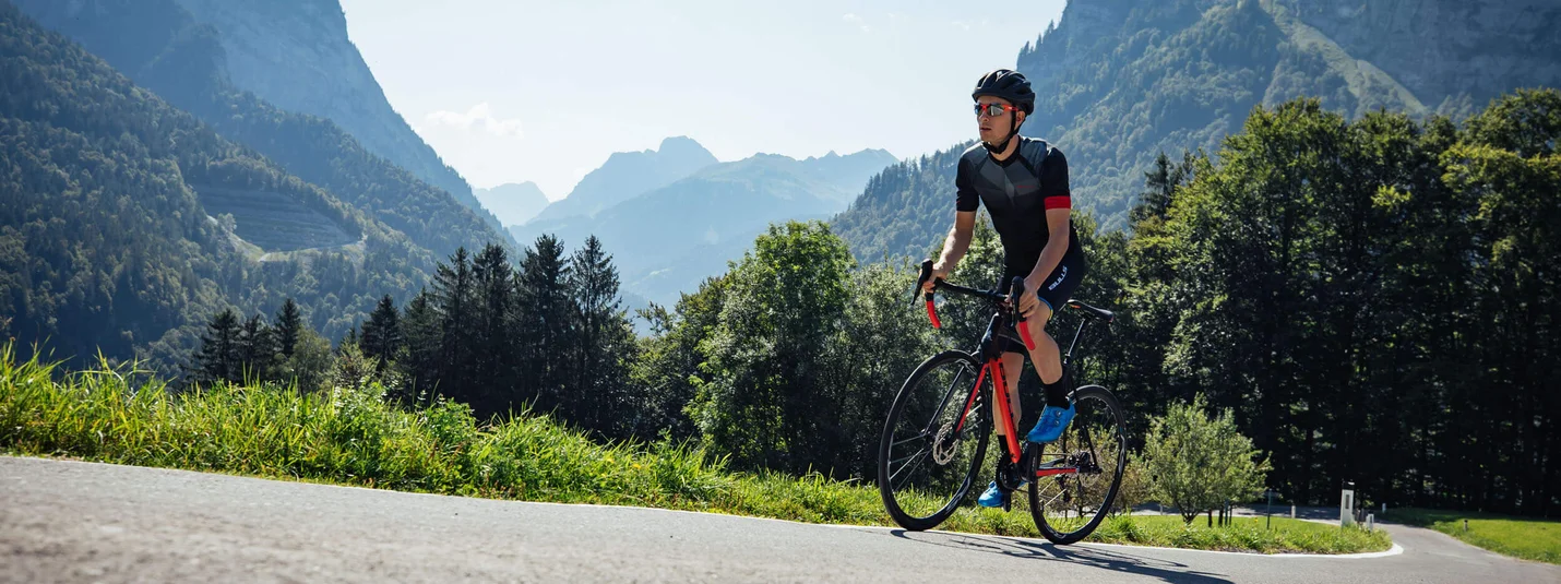 Bregenzerwald - Lechtal - Allgäu © Bregenzerwald Tourismus - Sebastian Stiphout Cyclist wearing helmet rides on mountain road on a sunny day