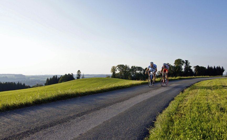 Due ciclisti su strada in una strada di campagna tra colline verdi