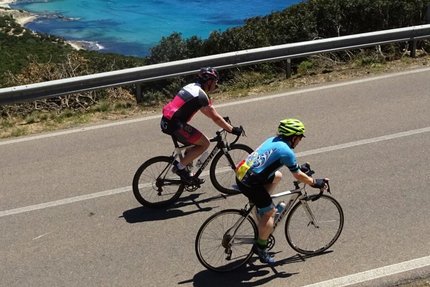 Due ciclisti sulla strada costiera con vista sul mare blu