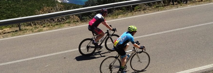 Due ciclisti sulla strada costiera con vista sul mare blu