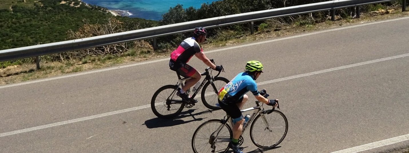 Due ciclisti sulla strada costiera con vista sul mare blu