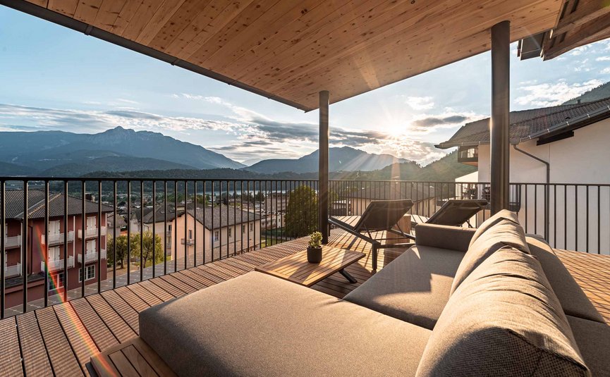 Balcone con divano e sdraio con vista sulle montagne al tramonto