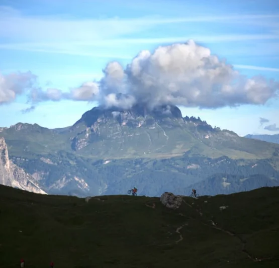 Berglandschap met wolken boven top en fietsers op pad