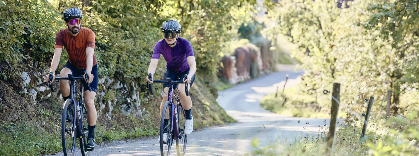 Foresta Nera Super divertente © Tobias Köhler Due ciclisti su una strada di campagna con vegetazione verde e sole