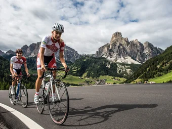 Alta Badia © Paola Finali Two road cyclists riding on a mountain road under cloudy sky