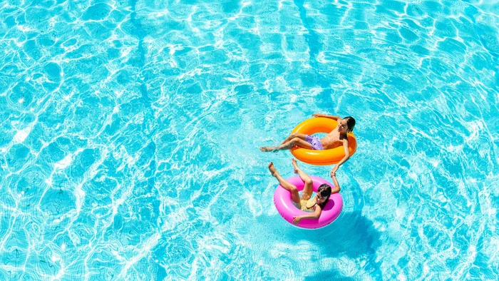 Rennradfrühling an der Ligurischen Riviera © Paolo Penni Martelli Zwei Kinder auf bunten Schwimmreifen im blauen Swimmingpool