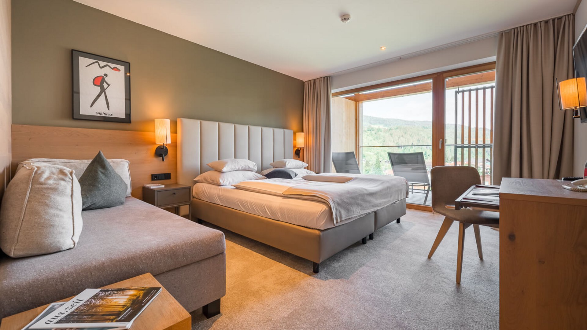 Moderne Hotelzimmer mit Doppelbett, Sofa und Balkon mit Bergblick