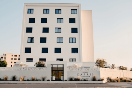Hotel Capris © Hotel Capris Capodistria Boutique Modern wit hotelgebouw met zwarte luiken en naam op de gevel
