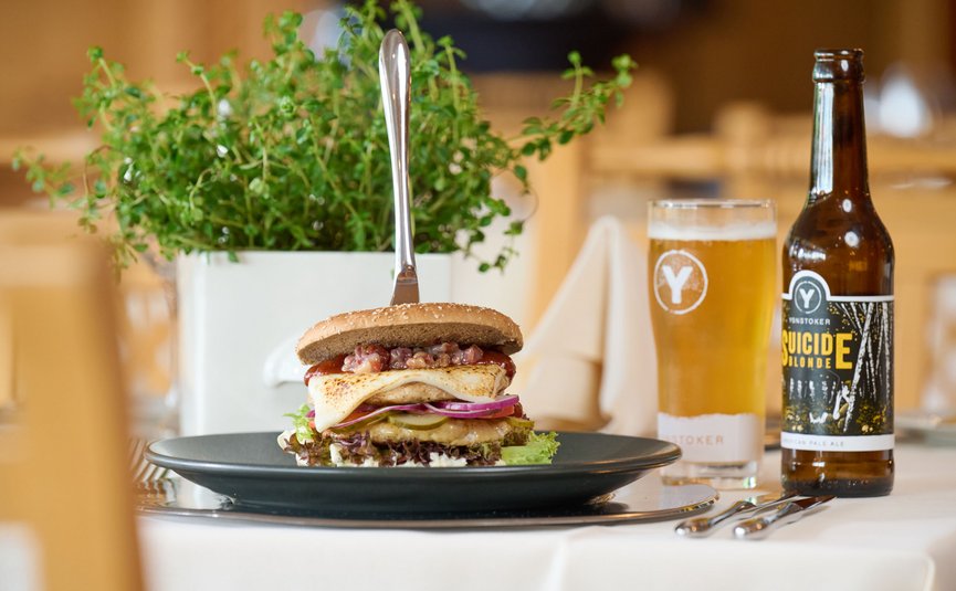 Burger con verdure e birra su tavolo apparecchiato